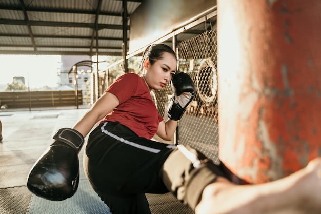 Vrouw vechter oefenen enkele trappen met een bokszak op bokskamp