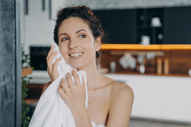 Vrouw veegt de gezichtshuid af met een handdoek na het wassen in de ochtend thuis Dagelijkse huidverzorgingsroutine