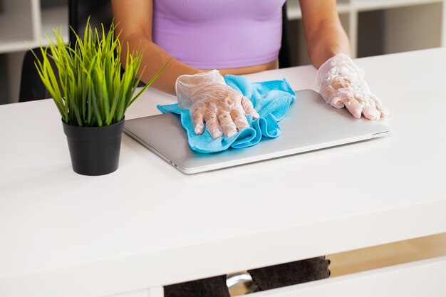 Vrouw veegt de laptop af met een vochtig desinfecterend doekje