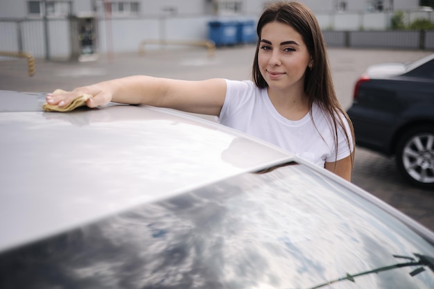 Vrouw veegt de voorruit van zijn auto af met een vod in een showroom bij een zelfbedieningswasstraat