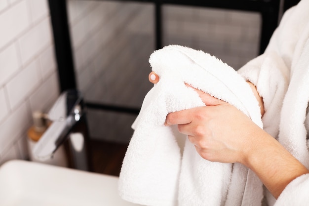 Vrouw veegt haar handen in een handdoek in een lichte badkamer.