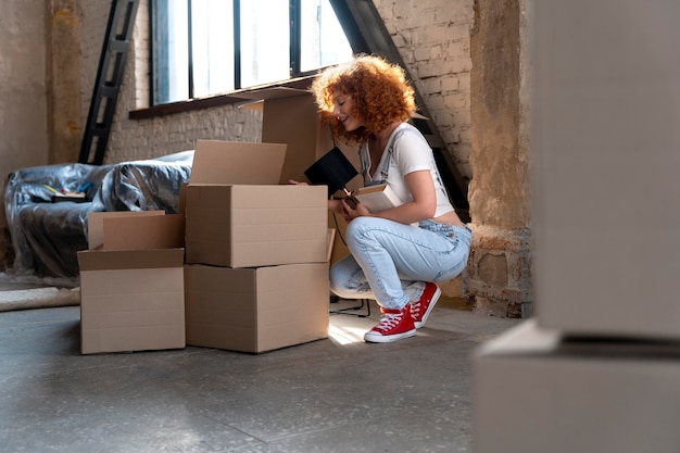 Foto vrouw verhuist naar nieuw huis en sorteert kartonnen dozen met spullen