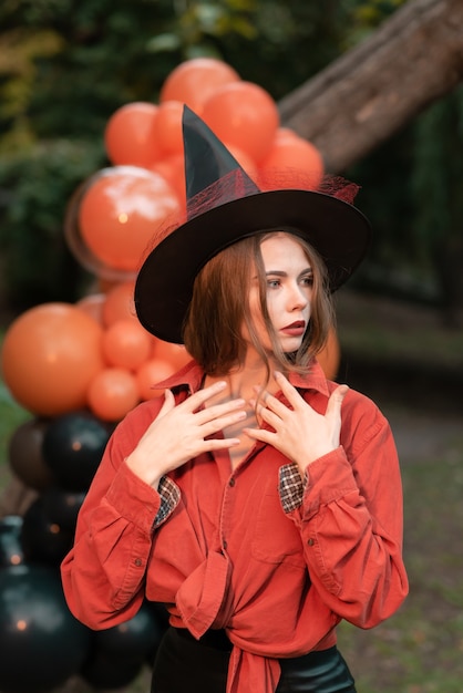 Vrouw verkleed als heks voor Halloween. Oranje ballen op de achtergrond van het bos. Halloween