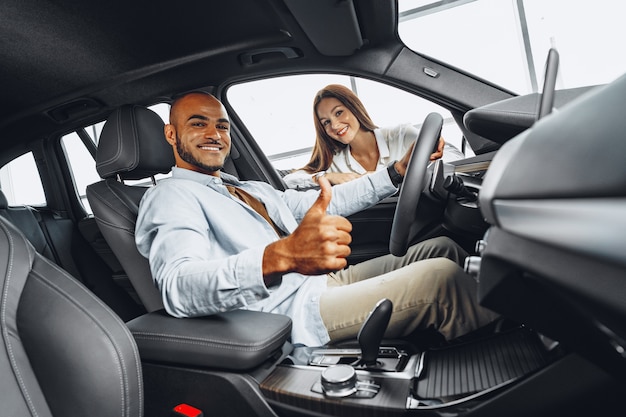 Vrouw verkoper in autoshowroom met een auto aan haar mannelijke klant