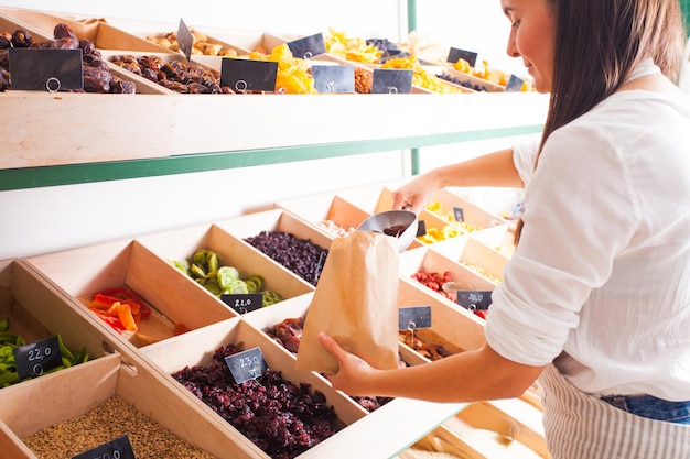 Vrouw verpakt gedroogde abrikozen in de kruidenierswinkel. Gedroogd fruit in de houten kisten, veganistisch eten