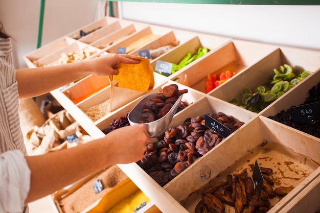 Vrouw verpakt gedroogde abrikozen in de kruidenierswinkel. Gedroogd fruit in de houten kisten, veganistisch eten