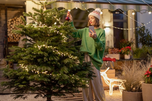 Vrouw versieren kerstboom in achtertuin