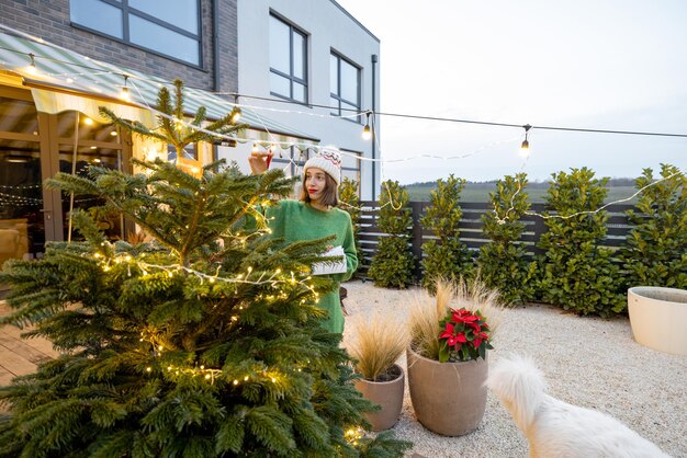 Vrouw versieren kerstboom in achtertuin