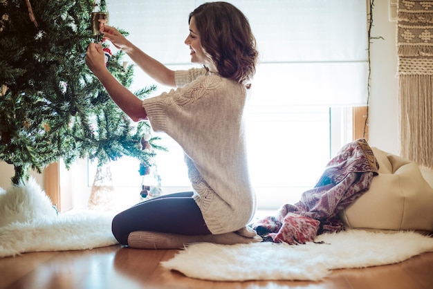 Vrouw versieren kerstboom thuis - Winterseizoen