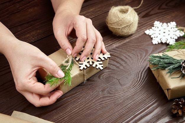 Vrouw versieren kerstcadeautjes op houten tafel