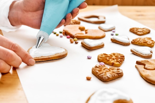 Foto vrouw versiert hartvormige koekjes met glazuur