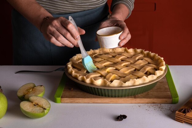 Vrouw verspreidt eieren op de rauwe appeltaart met een kookborstel in een bakkerij schotel klaar om in de oven te zetten Thanksgiving taart bereiding herfst bakkerij Crispy weer snoep Recept