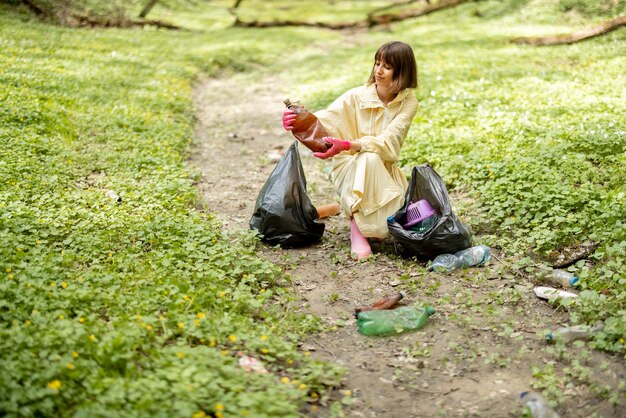 Vrouw verzamelt verspreid plastic afval in het bos