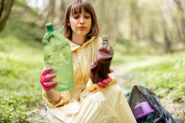 Foto vrouw verzamelt verspreid plastic afval in het bos