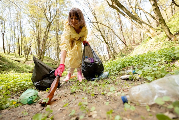 Vrouw verzamelt verspreid plastic afval in het bos