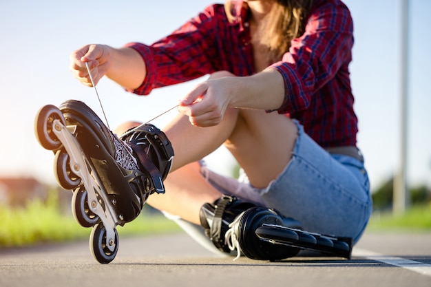 Vrouw veters rolschaatsen voor inline skaten. Tiener skaten buitenshuis.