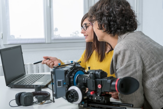 Vrouw video-editor en jonge assistent met behulp van grafische tablet