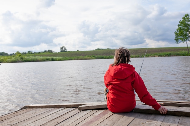 Vrouw visser zit met haar rug naar de kijker en houdt een hengel in haar hand vrouw vangt een vis meisje aan het vissen