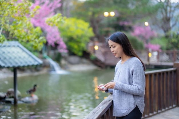 Vrouw voedt de karpervissen in de tuin met watervijver