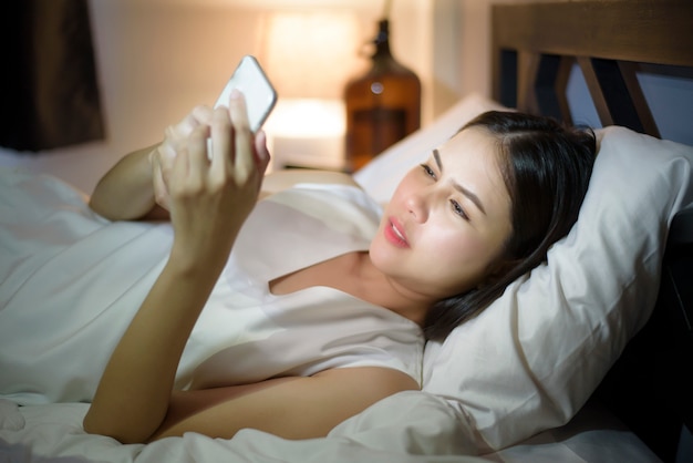 Vrouw voelt oogpijn bij het gebruik van slimme telefoon 's nachts