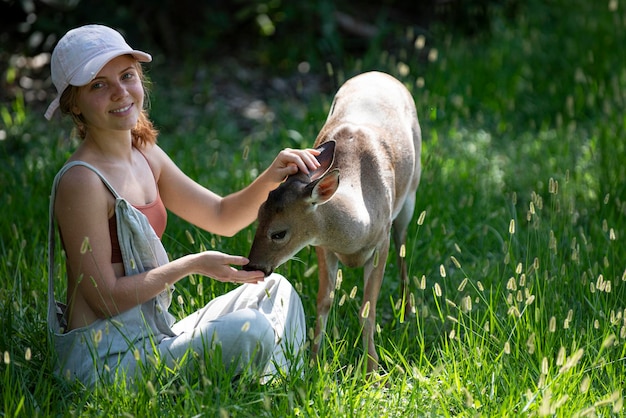 Vrouw voert bambi herten. Eenheid met de natuur. Wilde dieren concept. Meisje voedende reekalf. Dier in het park.