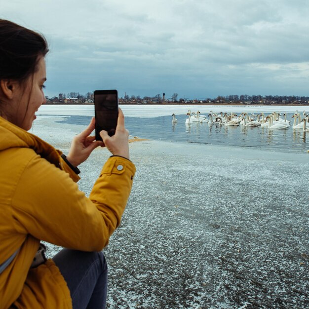 Vrouw voert zwanen op bevroren wintermeer