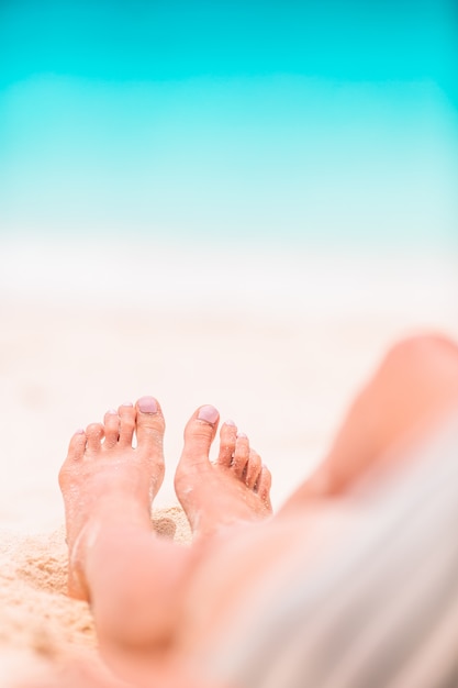 Vrouw voeten op het witte zandstrand in ondiep water