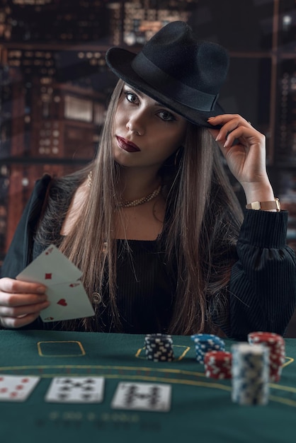 Vrouw voor het winnen van een pokerspel met twee azen in de hand aan de speeltafel