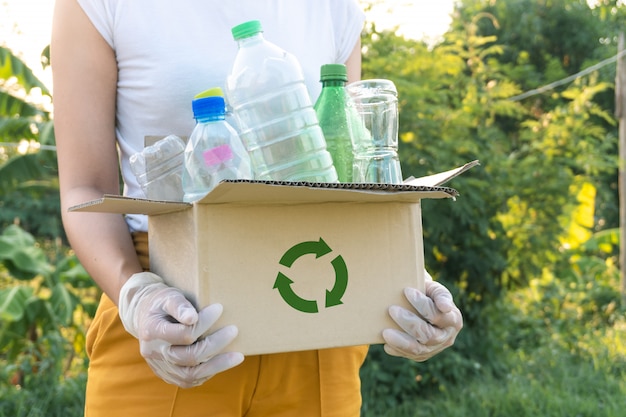 Vrouw vuilnis plastic flessen oppakken in een doos voor recycling concept