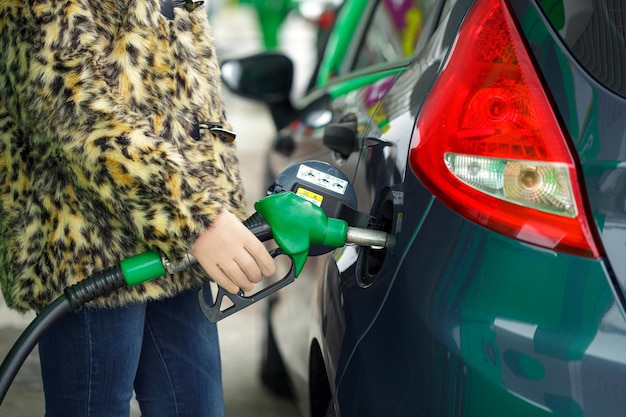 Foto vrouw vult benzine in haar auto bij een tankstation in de winter close-up