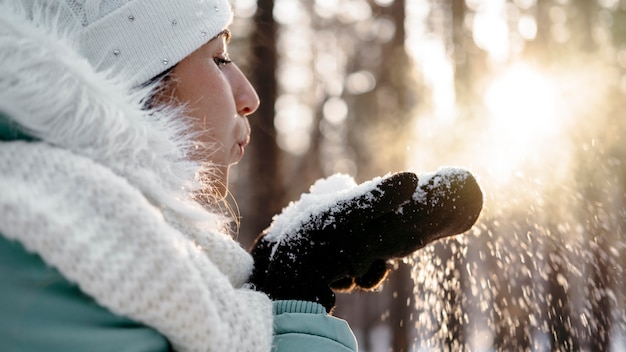 Vrouw waait sneeuw buiten in de winter