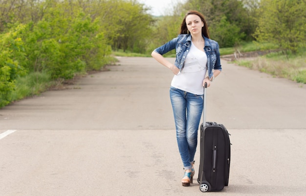 Vrouw wacht op de weg met haar koffer