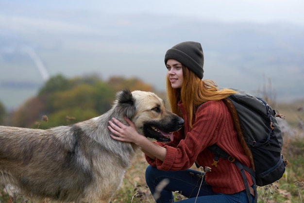 Foto vrouw wandelaar met een rugzak loopt de hond in de bergen in de natuur