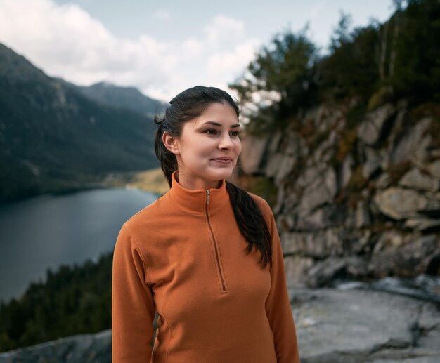 Vrouw wandelaar op de top van de berg Concept van avontuurlijke vakanties Reiziger millennial meisje verblijft op de rand van de klif met herfstbos en geniet van een prachtig uitzicht op de vallei