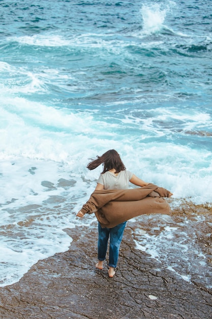 Vrouw wandelen door rotsachtig strand in natte jeans op blote voeten zomer zee vakantie