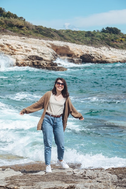 Vrouw wandelen door rotsachtige zee strand op zonnige winderige dag zomervakantie