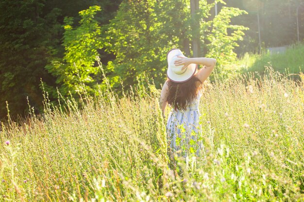 Vrouw wandelen in een veld in de zomer zonnige dag achterkant uitzicht