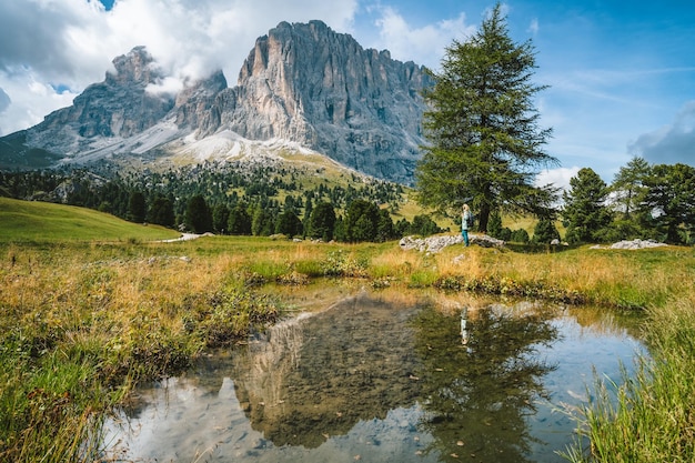 Vrouw wandelen in Val Gardena Pond en reflectie van Sassolungo Langkofel berg Dolomieten Italië