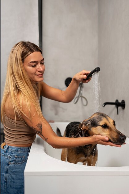 Foto vrouw wassen hond in badkuip zijaanzicht