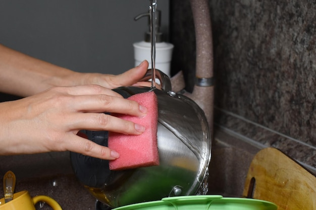 Vrouw wast afwas in de gootsteen in de keuken. huisvrouw wast vuile vaat thuis.