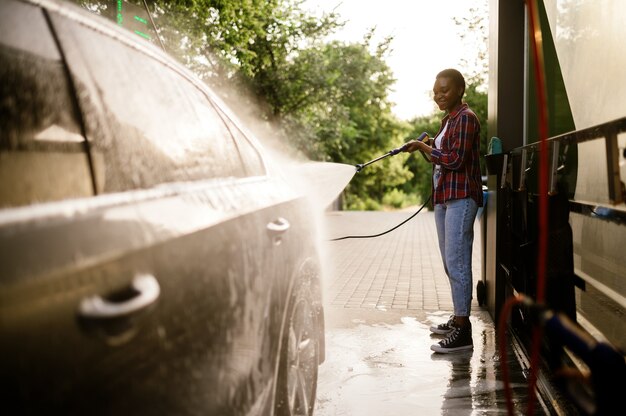 Vrouw wast schuim uit de auto, auto wassen met de hand