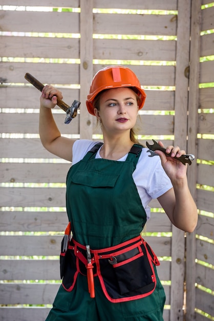 Vrouw werknemer met tools. Jong meisje in overall en helm die zich voordeed op de bouwplaats