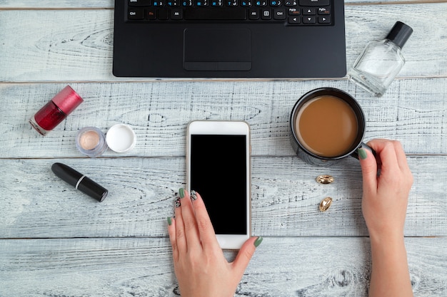 vrouw werkplek met vrouwenhanden, smartphone, laptop, koffiekopje en cosmetica