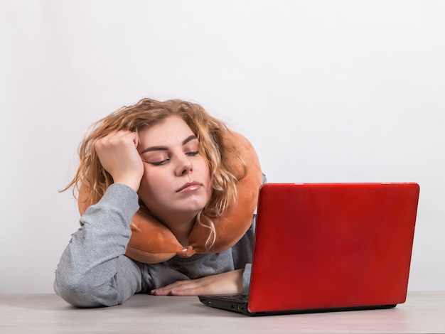 vrouw werkt op de computer met kussen om haar nek op wit.