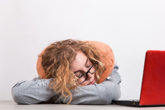 Vrouw werkt op de computer met kussen om haar nek op wit.