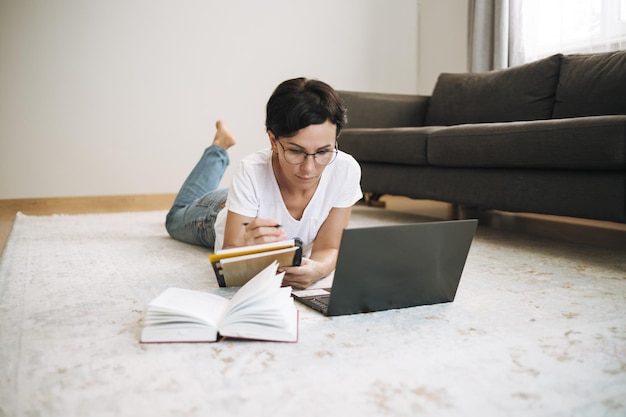 Vrouw werkt op een laptop vanuit huis aantrekkelijke brunette van middelbare leeftijd met computer