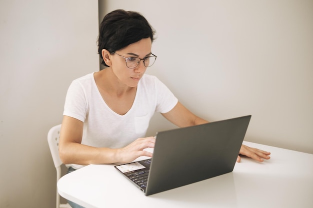 Vrouw werkt op een laptop vanuit huis Aantrekkelijke brunette van middelbare leeftijd met computer