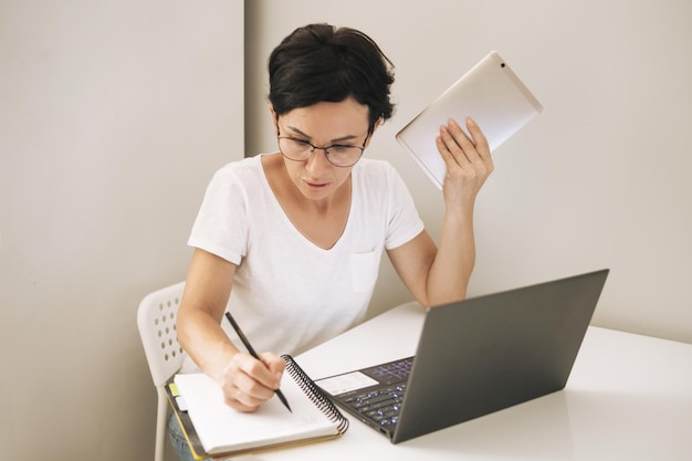 Vrouw werkt op een laptop vanuit huis Aantrekkelijke brunette van middelbare leeftijd met computer