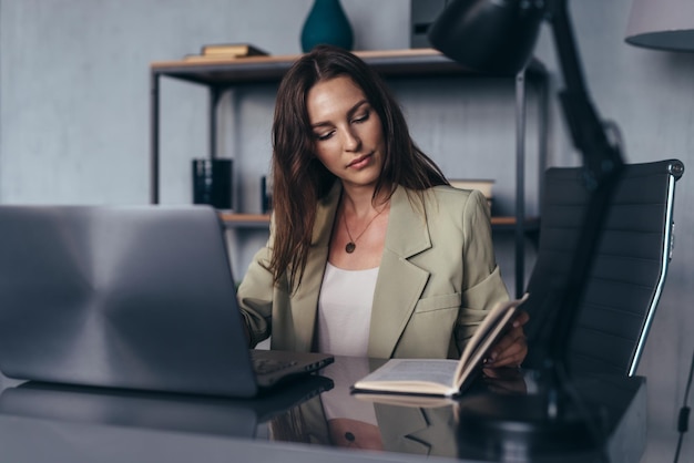 Vrouw werkt op kantoor zittend aan haar bureau met haar laptop