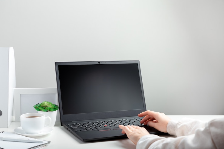 Foto vrouw werkt op laptop in online onderwijs op witte werkruimte. vrouwelijke handen typen op laptop. zwart laptopscherm mock up leeg. werkplek in thuiskantoor voor werken op afstand in minimalistische stijl.